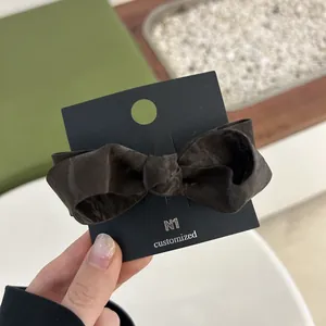 Detail of dark brown silk ribbon bow hair clip on premium black display card