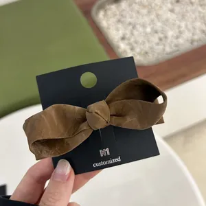Detailed view of a brown bow hair clip with matte texture on a black display card