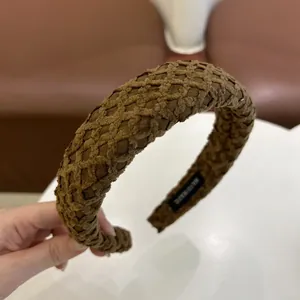 Detailopname van de handgemaakte bruine gevlochten haarband met ruitjestextuur