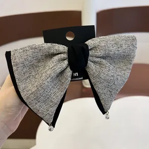 Détail d'une pince à cheveux nœud en tweed gris avec d'élégants pendentifs en cristal