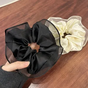Detailed macro view of black and beige satin hair scrunchies with elegant mesh lace edges