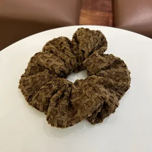 Detailopname van een diepbruine scrunchie met wafelstructuur op witte tafel