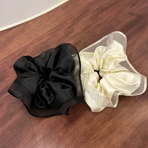Close-up of black and cream satin scrunchies with sheer organza ruffles and silk texture