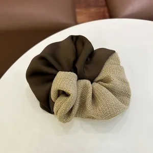 Détail d'un chouchou rétro mêlant satin marron lisse et lin beige à texture naturelle