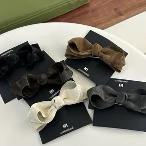 Five textured bow hair clips in black, brown, and grey colors on display cards