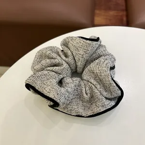 Gros plan sur un chouchou en tweed gris avec bordure noire et texture tissée