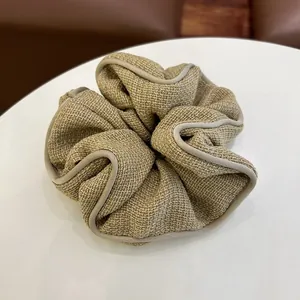Vue détaillée du tissu kaki texturé et du liseré lisse sur le chouchou surdimensionné