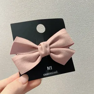 Barrette à nœud en daim rose présentée sur carte noire, style vintage et minimaliste
