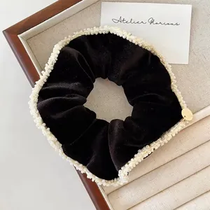 Elegant black velvet scrunchie with white pearl trim and a golden charm detail