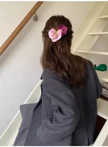 Rear view of pink and purple orchid hair clips styled on long brunette wavy hair