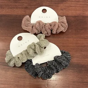Gedetailleerde textuur van drie geplooide metallic scrunchies in brons, goud en zwart
