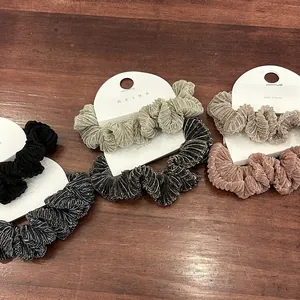 Detailopname van vijf metallic zijden scrunchies in neutrale tinten op houtoppervlak