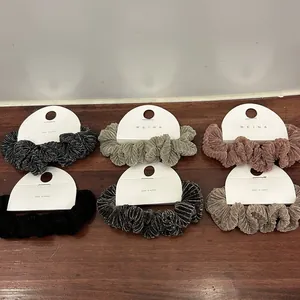 Detail van zes getextureerde scrunchies in fluweel en zijden stoffen op hout