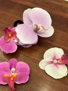 Detailed view of artificial orchid hair clips with realistic fabric petals and pearl centers