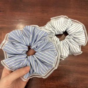 Blue and white striped scrunchies with white lace trim shown on a wooden background