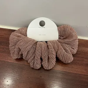 Detailed macro view of rose gold metallic silk scrunchie with elegant pleated texture