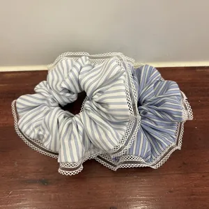 Blue and white striped scrunchies with white lace edges on a wooden surface