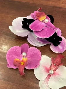 Detail of faux orchid hair claw clips with vibrant pink petals and centered white pearls