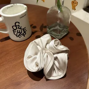 Detail of oversized cream satin scrunchie with silk texture on wooden table