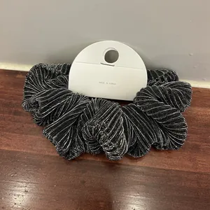 Close-up of black metallic shimmer scrunchie with pleated texture on display card