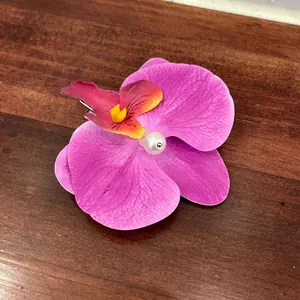 Macro detail of orchid hair claw clip with purple petals and center pearl on wood