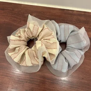 Close-up of beige and grey-blue striped hair scrunchies with sheer organza lace trim