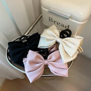 Three-color set of large satin bow hair clips in black, cream, and pink with shark claw