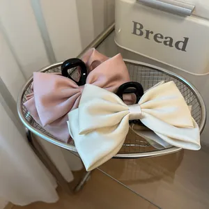 Detail of large satin bow hair claw clips in pink and cream with non-slip teeth