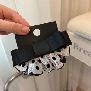 Detail einer schwarzen Schleife Haarklammer mit weißen Punkten auf Mesh-Gewebe