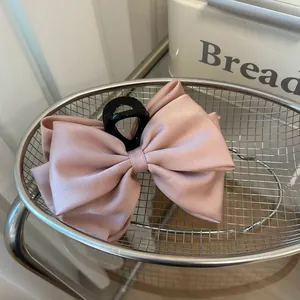 Detail of a large pink satin bow hair claw clip in a minimalist stainless steel basket
