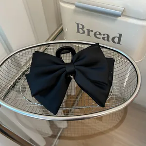 Macro detail of large black satin double bow hair claw clip in a woven metal basket