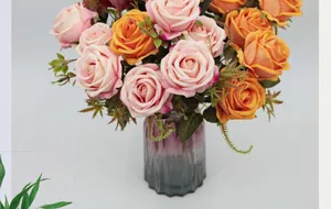 Detalle de rosas de terciopelo rosa y naranja en un jarrón de cristal morado texturizado