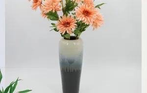 Dettaglio di un vaso moderno in ceramica sfumato blu con fiori artificiali arancioni