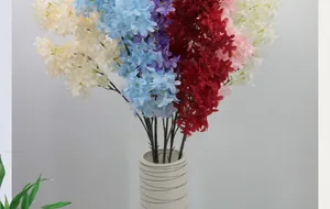Close-up of mixed silk cherry blossoms in a modern black-striped white ceramic vase