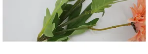 Dettaglio ravvicinato di steli di girasole artificiale e foglie verdi seghettate su bianco
