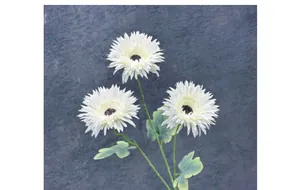 Dettaglio macro di gerbera artificiale bianca a tre teste con foglie verdi realistiche