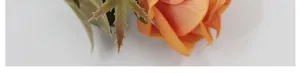 Primer plano de pétalos de rosa artificial de terciopelo naranja y hojas verdes