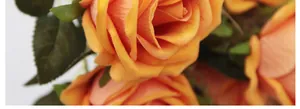 Detalle macro de rosas artificiales con pétalos de terciopelo naranja vibrante y hojas