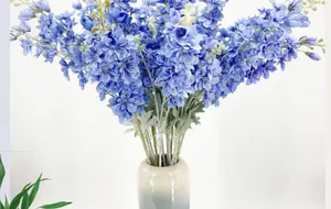 Detailed view of blue artificial delphinium flowers in a stylish ceramic vase
