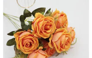 Primer plano de un ramo de rosas artificiales de terciopelo naranja con hojas realistas