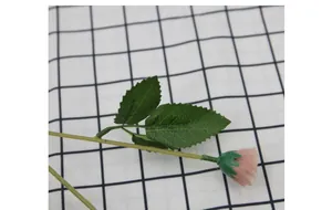 Dettaglio di boccioli di rose artificiali rosa con foglie su tovaglia a quadretti