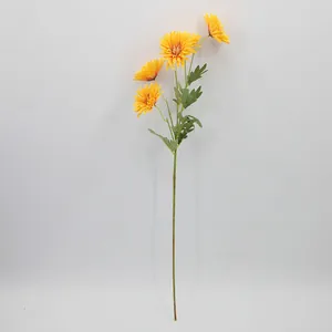 Ramo di gerbera artificiale gialla con cinque fiori e foglie verdi su sfondo bianco neutro