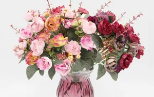 Close-up of artificial autumn rose bouquet in a purple textured glass vase for decor