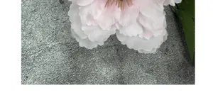 Makroaufnahme von rosa künstlichen Päonienblütenblättern auf grauem Steintexturhintergrund