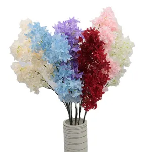 Vibrant artificial cherry blossom stems in various colors with minimalist white vase