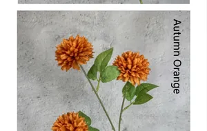 Close-up of autumn orange pompon mum artificial flowers with realistic green leaves