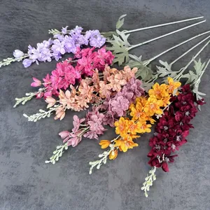 Delphinium artificial silk flowers in multiple colors arranged on a textured grey surface