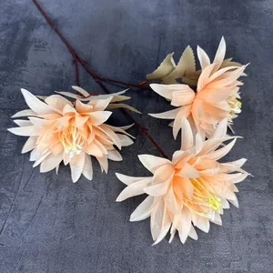 Bouquet de trois têtes de chrysanthèmes artificiels orange abricot sur fond de pierre grise