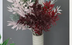 Close-up of artificial willow leaves in various colors inside a ceramic striped vase