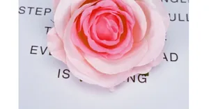 Primo piano di una testa di rosa artificiale in seta rosa con petali sfumati realistici